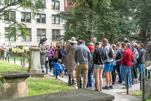 Tomb of Paul Revere in Granary Burying Ground in Boston, Massachusetts, USA. There are a group of tourists being given a guided tour by a guide in a period costume.