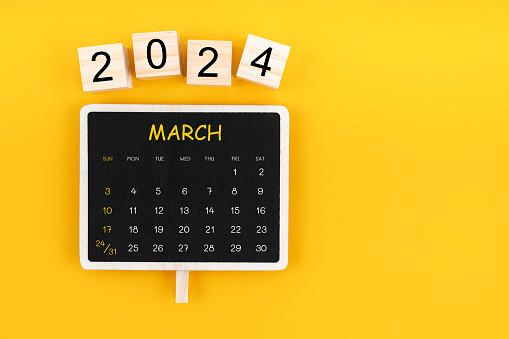 Calendar for March 2024 in black chalkboard with copy space on a yellow color background.