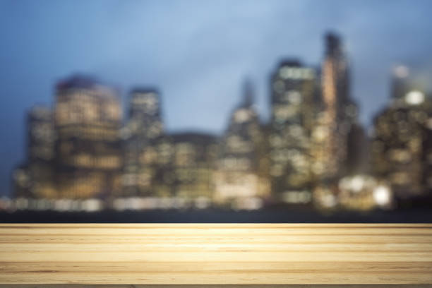 istock Empty wooden tabletop with beautiful blurry skyscrapers at evening on background, mock up 1802168865