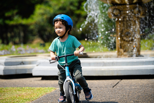 boy driving balance bike outdoors on forest
