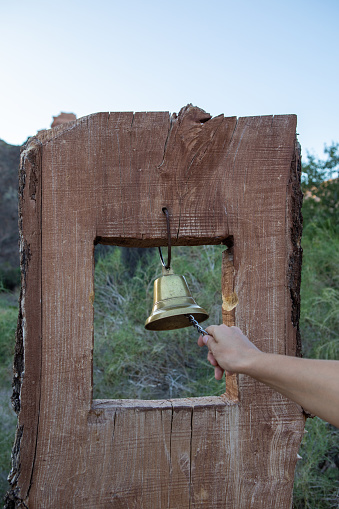 A golden bell hangs on the top of a mountain in the Charyn Canyon, through which you can see the peaks of brown mountains and the gorge.