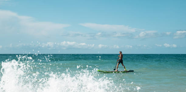 istock athletic wiry surfer guy swims with a paddle on a sapboard in the sea 1802245852
