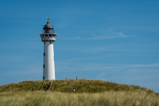 Montauk Point Lighthouse in Montauk Point State Park, Long Island, New York, in setting sunlight with Atlantic Ocean in the background.