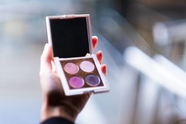 Hand with vibrant eyeshadow palette.