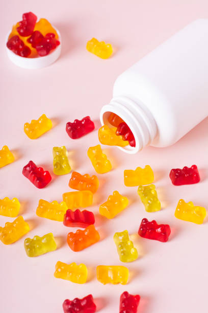 istock Group of gummy supplements with multivitamins and a bottle for them on a pink vertical view 1802289977