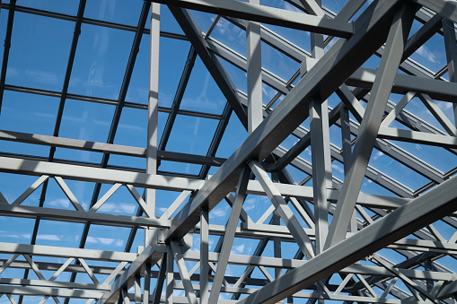 Glass roof against the blue sky. Construction made of steel supports and transparent glass.