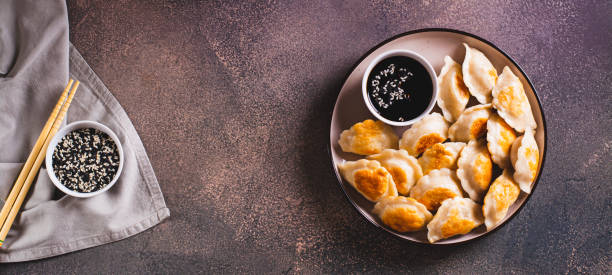 istock Crispy fried dumplings with soy sauce and sesame seeds on a plate top view web banner 1802295957