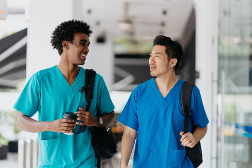 Asian and African healthcare worker in medical scrubs walking to work