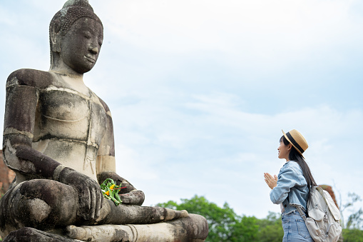 Asian women traveller  having praying during vacation in temple of the Ayutthaya buddha in Thailand.