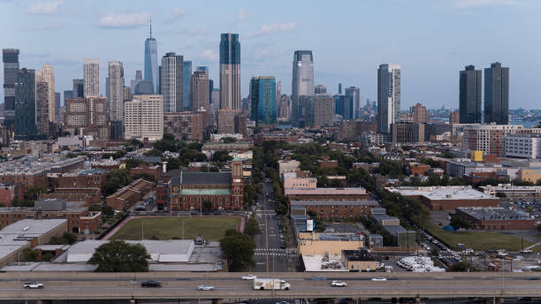 New Jersey Turnpike crossing Hamilton park in Jersey City, New Jersey. Financial and Business skyscrapers of the Manhattan Downtown shown in the distance vista aérea de los horizontes de los centros de manhattan y jersey city sobre los barrios residenciales de jersey city. tráfico de automóviles de la autopista de peaje de nueva jersey contra el parque hamilton y el horizonte del centro de jersey city, n