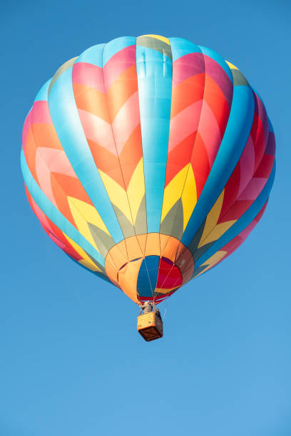 istock A brightly colored hot air balloon with a geometric pattern flying in a clear blue sky. 1802306496