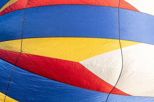 Abstract detail of the multicolored envelope of an inflating hot air balloon with primary colors and geometric arrow-shaped pattern.