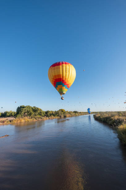istock A vibrant multicolor hot air balloon flies low over the Rio Grande River, its reflection visible in the surface of the water 1802310197