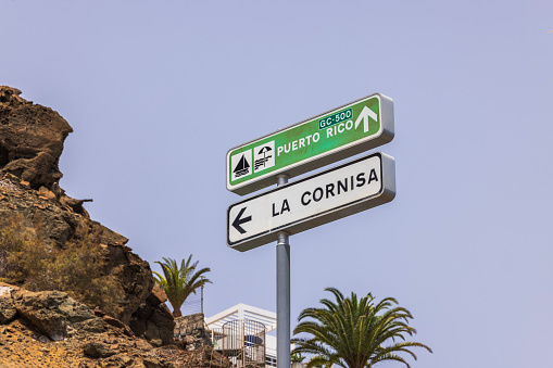 Close-up of signs indicating direction to Puerto Rico Beach and highway towards La Cornisa on island of Gran Canaria. Spain.