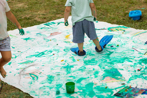 A bunch of children painting and playing with watercolor in the backyard
