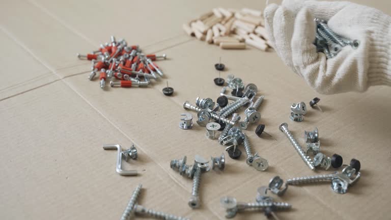 A male worker goes through the furniture fasteners after unpacking, preparing to assemble the furniture.