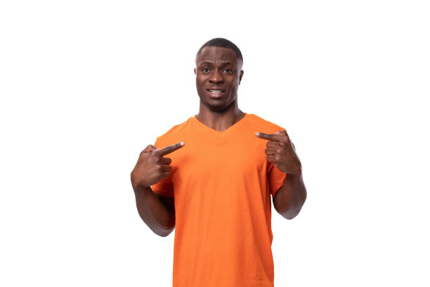 istock young american man dressed in basic orange t-shirt having doubts and suspicion on white background with copy space 1802342420