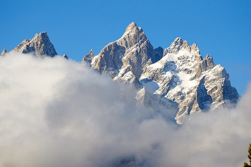 The snow-capped peaks of the Cathedral Group  (Teewinot Mountain, the Grand Teton and Mount Owen) are surrounded by a veil of clouds in Teton National Park.