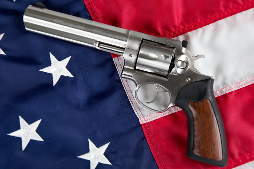 United States Second Amendment constitutional Right to Bear Arms. Antique firearm and veterans cap resting on an American Flag. Second Amendment constitutional Right to Bear Arms. 357 Magnum Revolver pistol resting on American Flag