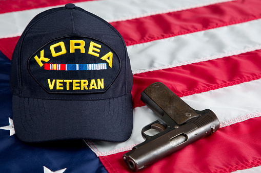 United States Second Amendment constitutional Right to Bear Arms. Antique firearm and veterans cap resting on an American Flag.