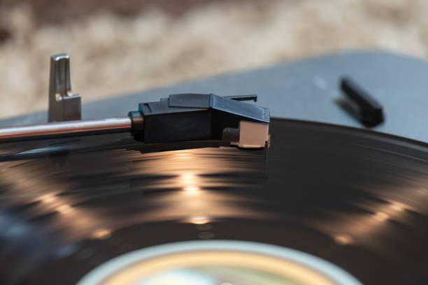 Close up of a vinyl record spinning on a turntable with light reflections accenting the surface of the disc.