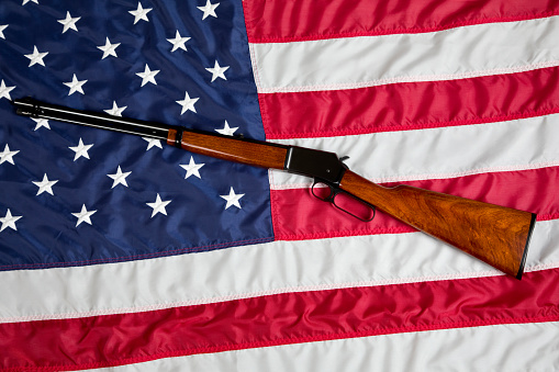 U.S. Second Amendment constitutional Right to Bear Arms. Lever action rifle resting on American Flag.