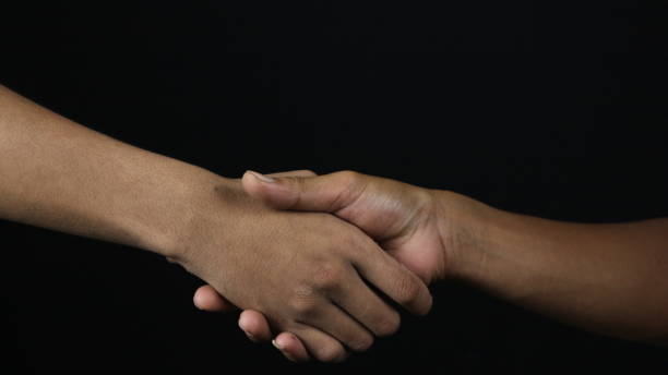istock Close up two man shaking hand as agreement on black background. 1802390727