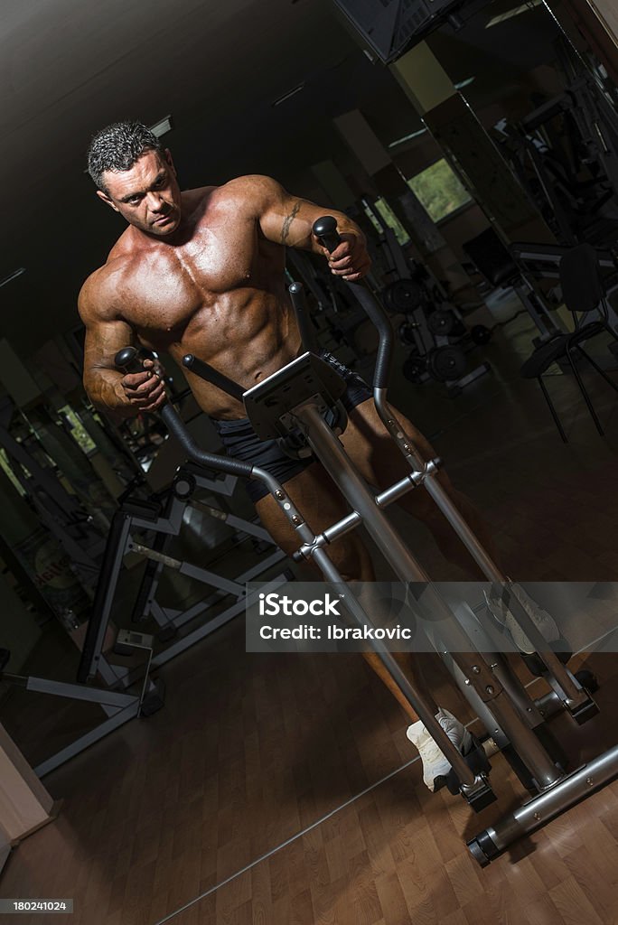 Macho bodybuilder usando la máquina elíptica - Foto de stock de Adulto libre de derechos