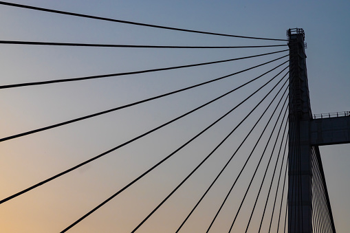 Cable stayed suspension bridge known as the Vidyasagar Setu built on the river Ganges at sunset with view of a boat seen from Princep Ghat at Kolkata, India
