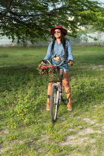 young woman standing next to the bicycle and looking up at the tree