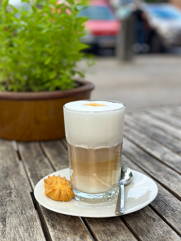 Caffe latte macchiato coffee layered with milk with a cookie