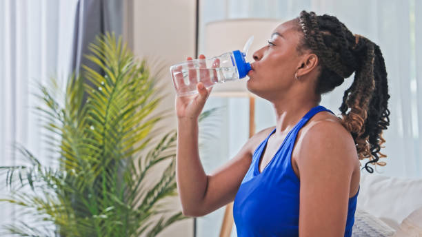 istock A woman drinking water after workout at home 1802438695