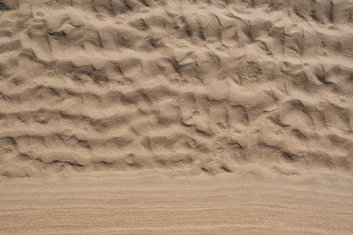 Beach sand background, with copy space at the bottom of the image. The coastal scenery offers a picturesque setting, with the waves gently lapping at the shore. A generous copy-space at the bottom of the image provides ample room for text or additional elements, making it an ideal backdrop for conveying messages related to vacations, relaxation, or any beach-themed content.