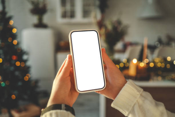 istock Phone in hands with isolated screen on Christmas kitchen background 1802466126