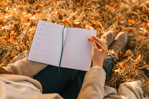 Girl with paper planner outdoors, autumn concept.