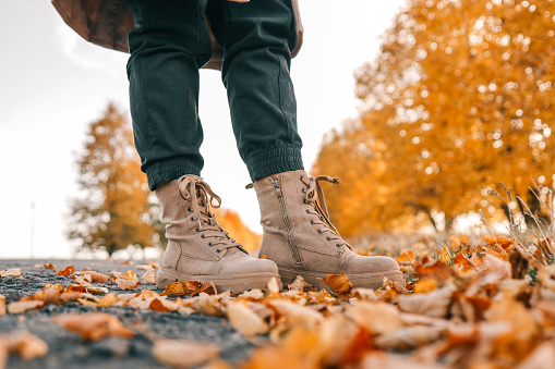 A man walks along an autumn road, boots close-up.