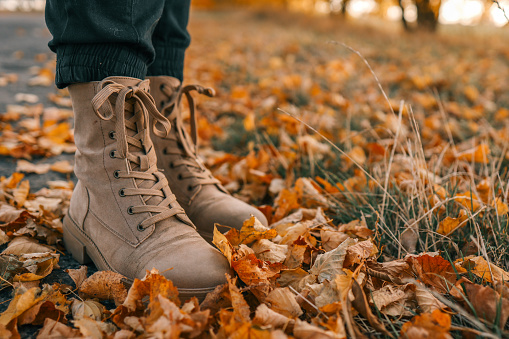 A man walks along an autumn road, boots close-up.