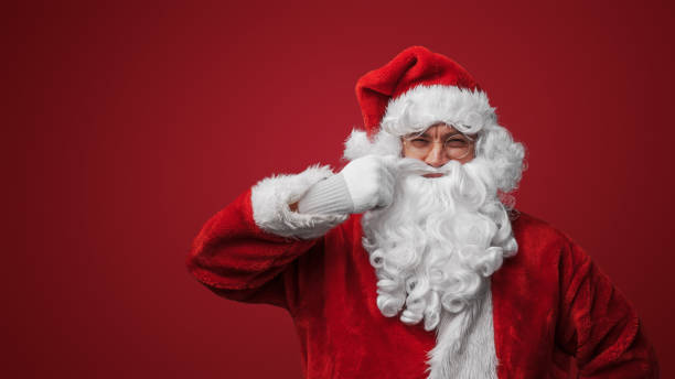 istock Xmas santa stroking his moustache against gray background 1802474364