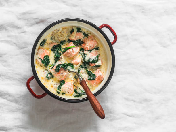 istock Salmon, cream, spinach sauce stew in a saucepan on a light background, top view 1802478003