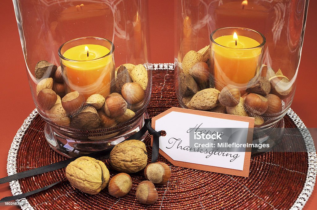 Beautiful Happy Thanksgiving table setting centerpiece Beautiful Happy Thanksgiving table setting centerpiece with ornage candle and nuts in decorative glass hurrican lamp vase and autumn arrangement Autumn Stock Photo
