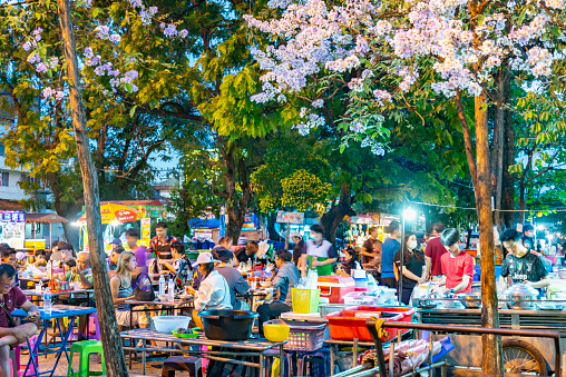 Chiang Mai,Thailand-March 20 2023: At sunset, between the old city walls and perimeter old town moat,customers and chefs come to cook and eat delicious local food, in beautiful floral surroundings.