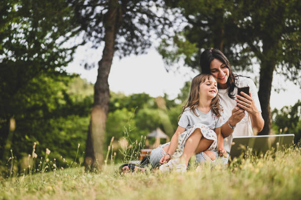 Mom with child having video call while relaxing in a parkland.