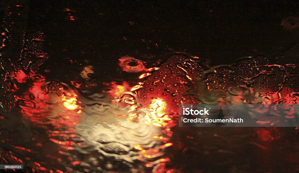 Driving in storm and Rain- Abstract background Traffic Lights through Rain water on Glass creating a abstract pattern on the windshield. Abstract Stock Photo