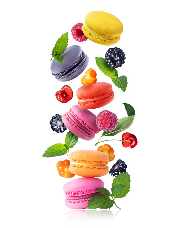 Ð¡olored macaroons with berries and mint leaves. Levitating colored macaroons with different flavors isolated on a white background