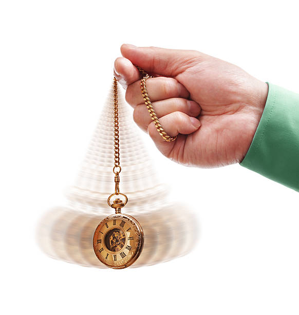 Hand holding a gold pocket watch swinging back and forth