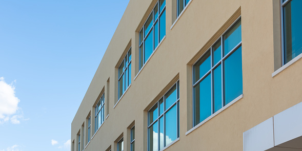 A modern building exterior with blue sky and blue reflected in the windows.
