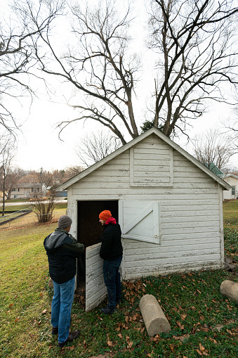 Two men look at the gate of the one horse stall barn in town, Rochester, MN, USA