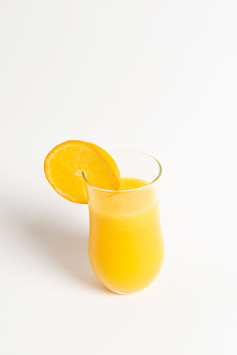 Front  view of orange fruit and glass of orange juice