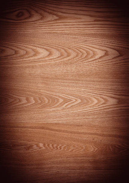 Weathered and scratched rustic wooden board.High angle view of a flat textured wooden board backgrounds. It has a beautiful nature and abstractive pattern. A close-up studio shooting shows details and lots of wood grain on the wood table. The piece of wood at the surface of the table also appears rich wooden material on it. The wood is dark brown color with darker brown lines and pattern on the bottom. Flat lay style. Its high-resolution textured quality.The close-up gives a direct view on the table, showing cracks and knotholes in the wood.