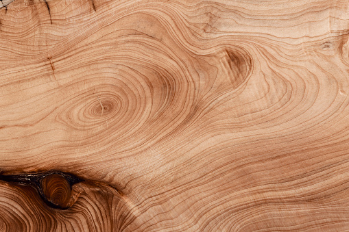 Weathered and scratched rustic wooden board.High angle view of a flat textured wooden board backgrounds. It has a beautiful nature and abstractive pattern. A close-up studio shooting shows details and lots of wood grain on the wood table. The piece of wood at the surface of the table also appears rich wooden material on it. The wood is dark brown color with darker brown lines and pattern on the bottom. Flat lay style. Its high-resolution textured quality.The close-up gives a direct view on the table, showing cracks and knotholes in the wood.